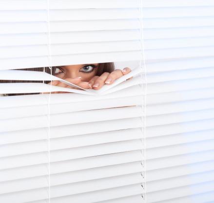 woman-peeking-through-window-blinds